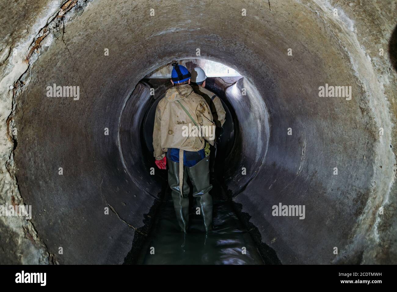 Sewer tunnel worker examines sewer system damage and wastewater leakage Stock Photo