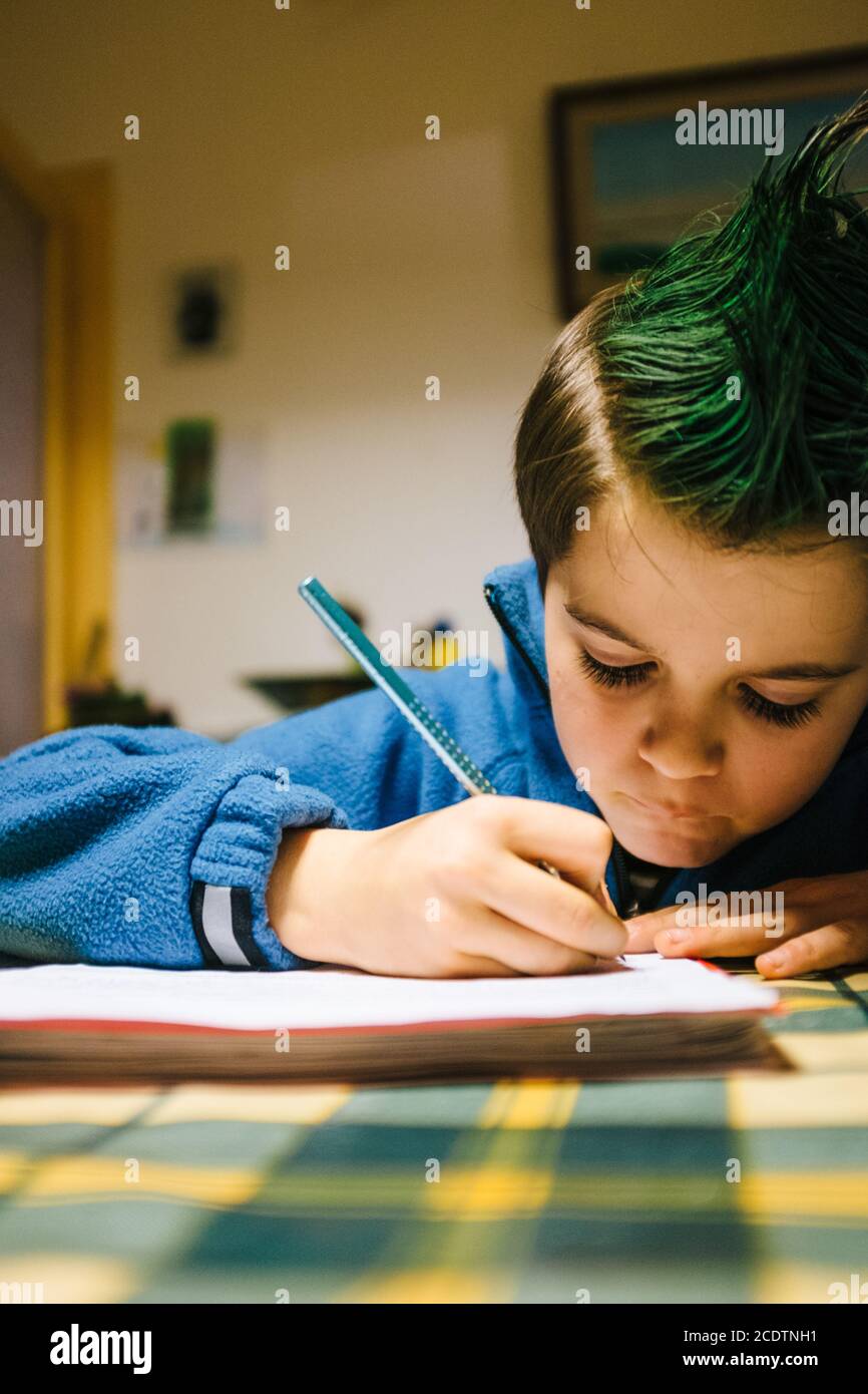portrait of 9 year old boy at home with green colored hair crest performing school homework Stock Photo