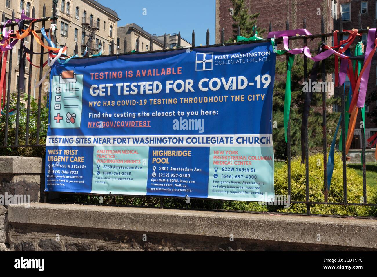 banner sign hanging from the gate of a church in Northern Manhattan promoting nearby testing sites for covid-19 or coronavirus during the pandemic Stock Photo