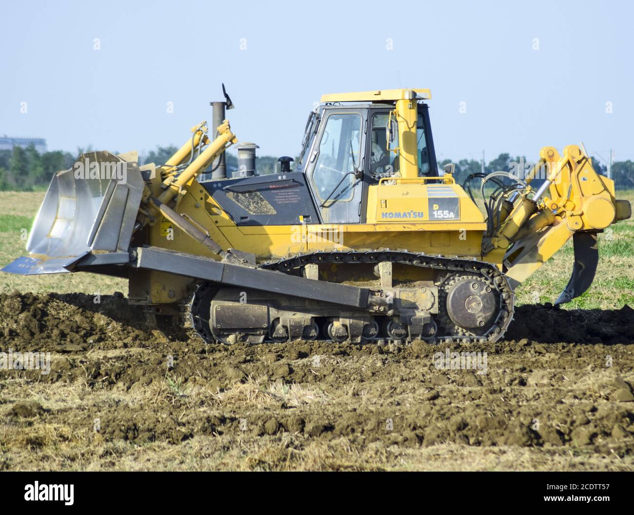 The yellow tractor with attached grederom makes ground leveling Stock