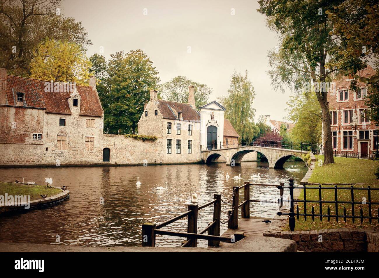 The Minnewater with bridge and entrance portal to the Bruges Beguinage De Wijngaard Stock Photo