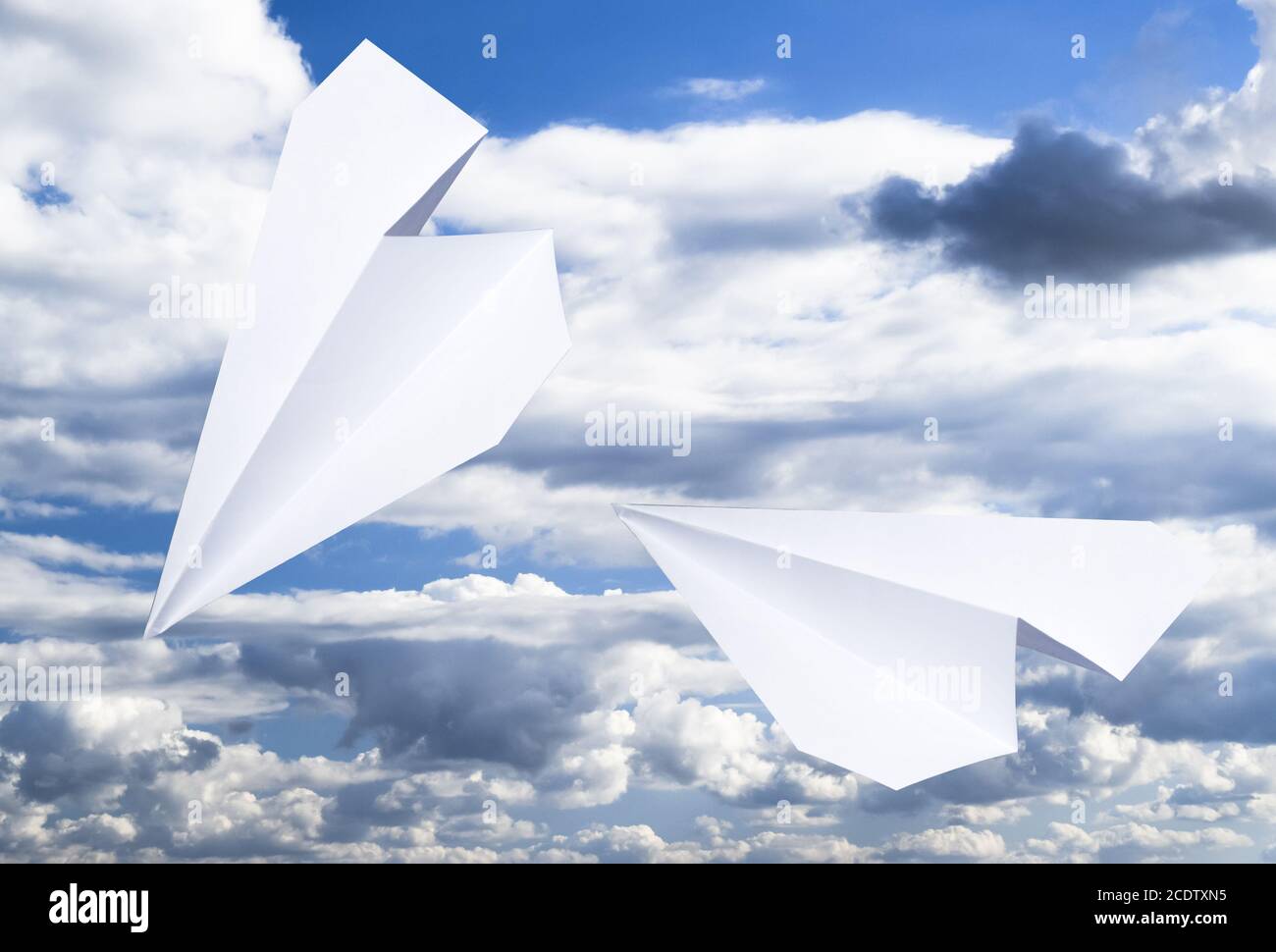 White paper airplane in a blue sky with clouds. The message symbol in ...