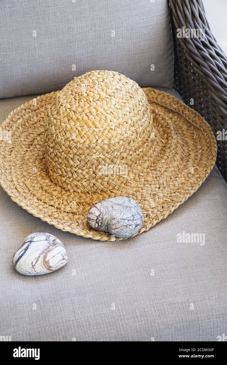 Straw hat with heart shaped rocks on chair Stock Photo