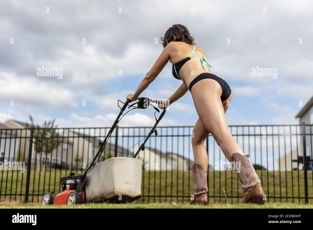 A Gorgeous Bikini Clad Model Mowing The Lawn Stock Photo