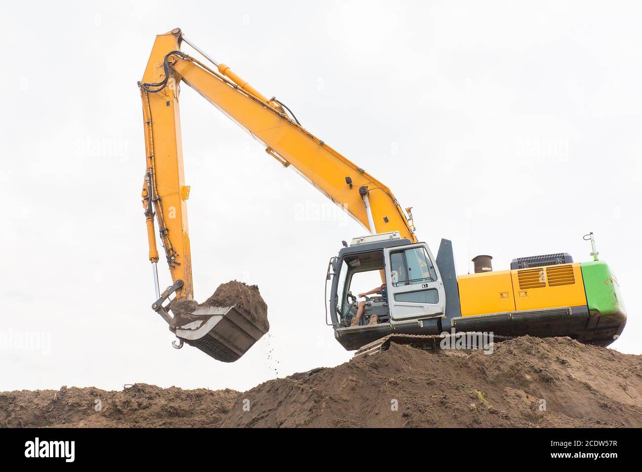 Excavator makes noise barrier with sandy soil Stock Photo