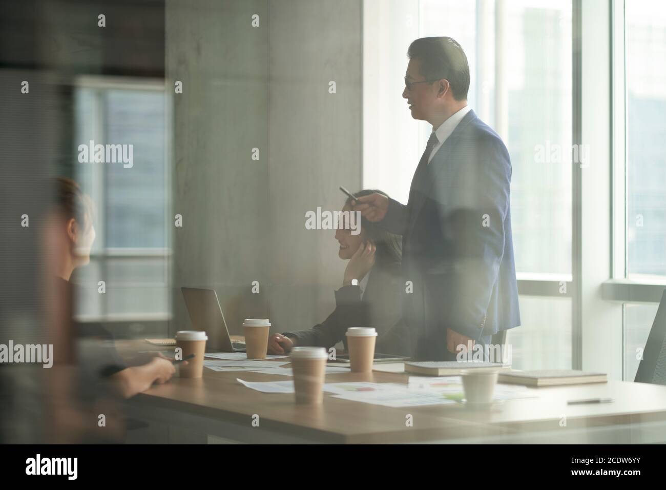 through-the-glass shot of a team of business people working meeting in office Stock Photo