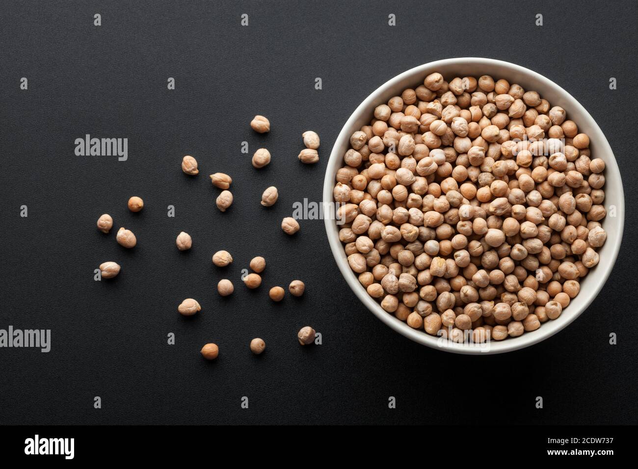 dry chickpeas in white bowl isolated on dark background. top view Stock Photo