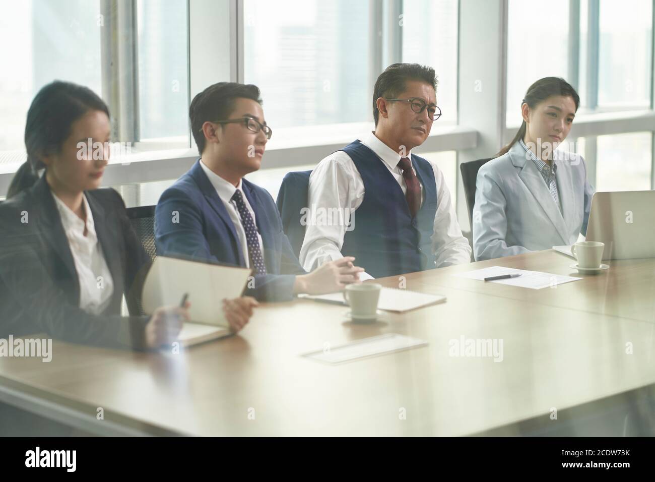 through-the-glass shot of a team of asian HR people interviewing candidate in office Stock Photo