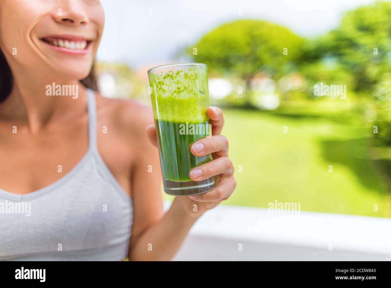 Green smoothie healthy lifestyle fitness woman drinking spinach juice cleanse in summer background at home. Happy fit girl living active life juicing Stock Photo