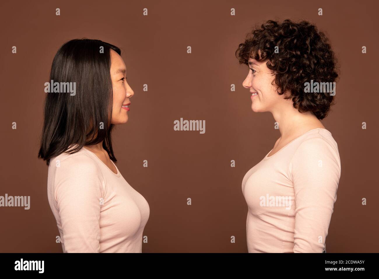Side view of two cheerful young females of Asian and Caucasian ethnicities Stock Photo