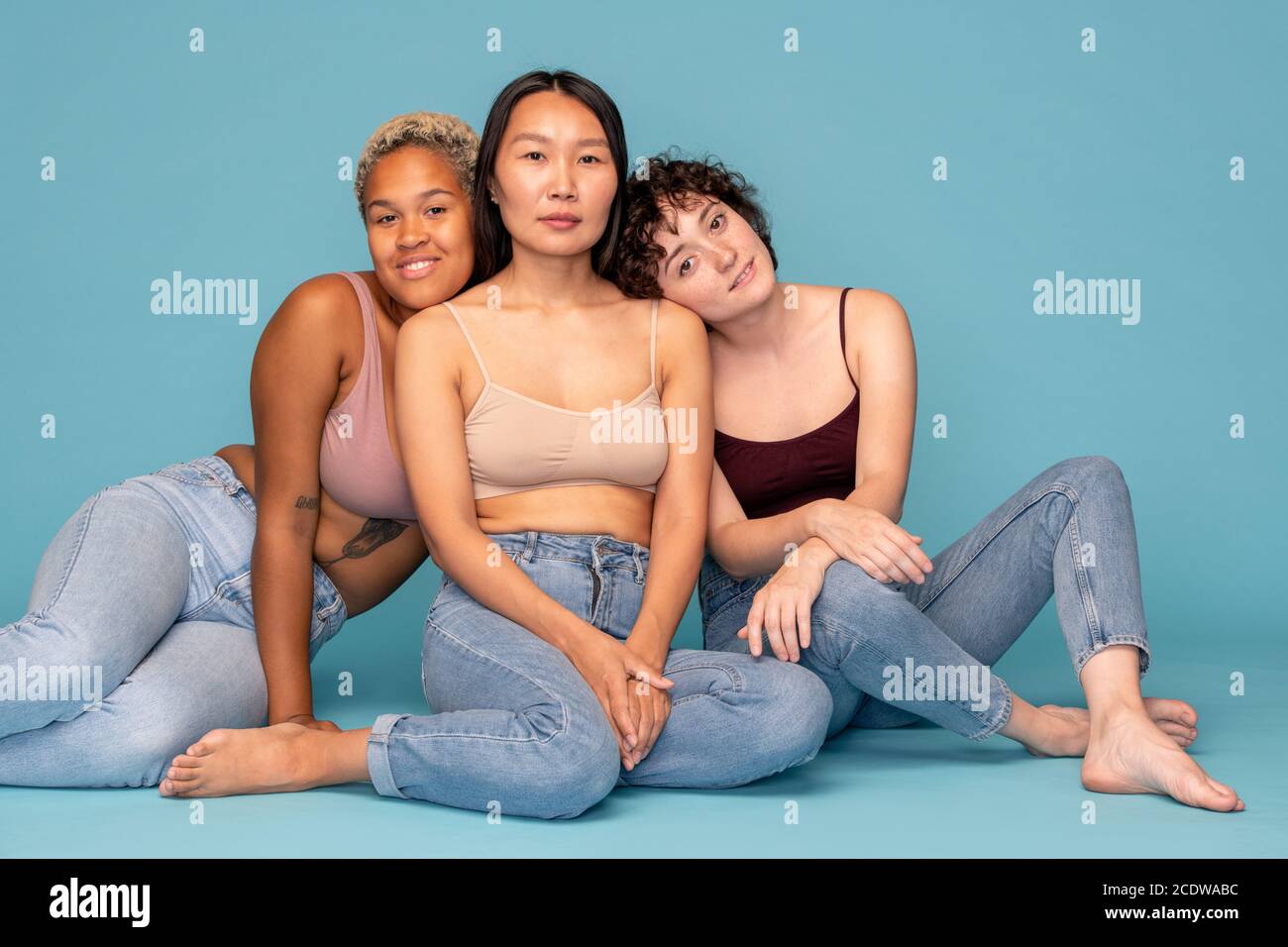 Three young affectionate and friendly women in tanktops and blue jeans Stock Photo