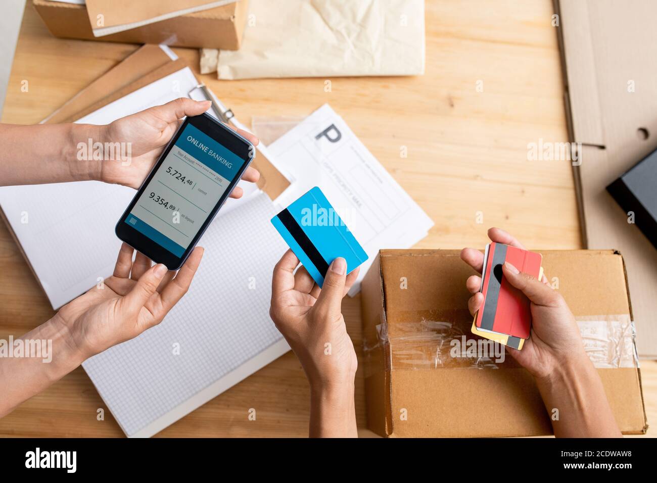 Overview of hands of two female managers holding smartphone and plastic cards Stock Photo