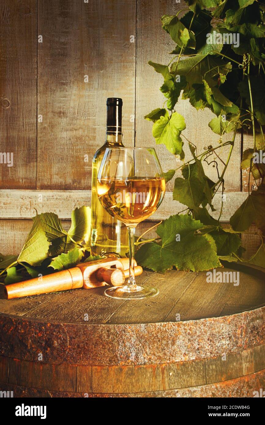 Closeup of bottle of white wine with glass on barrel Stock Photo