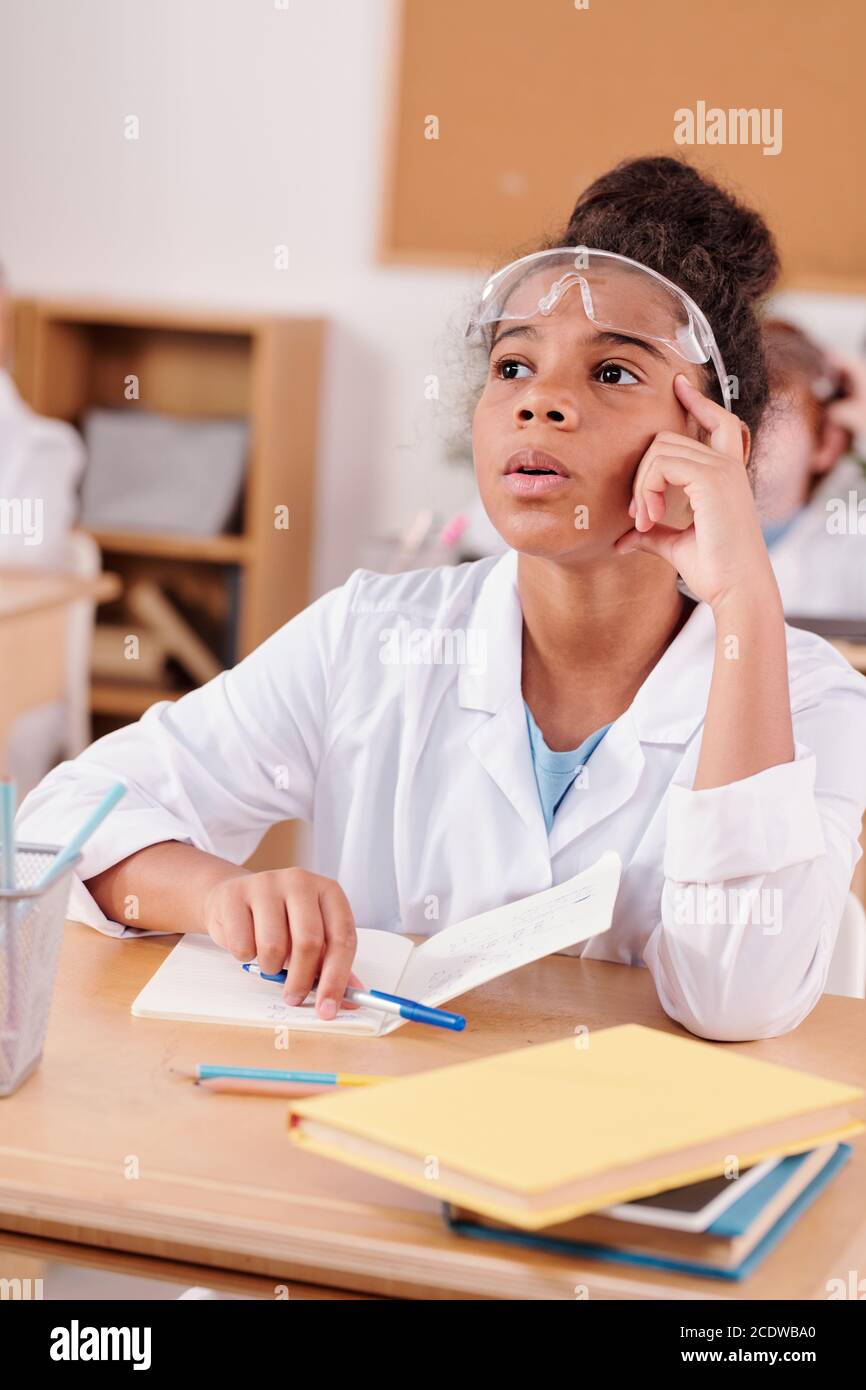 Contemporary schoolgirl of African ethnicity listening attentively at teacher Stock Photo