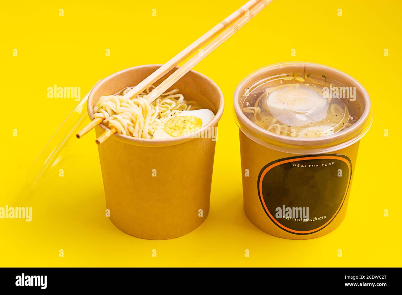 Chicken or vegetable broth with noodle and egg in craft containers on