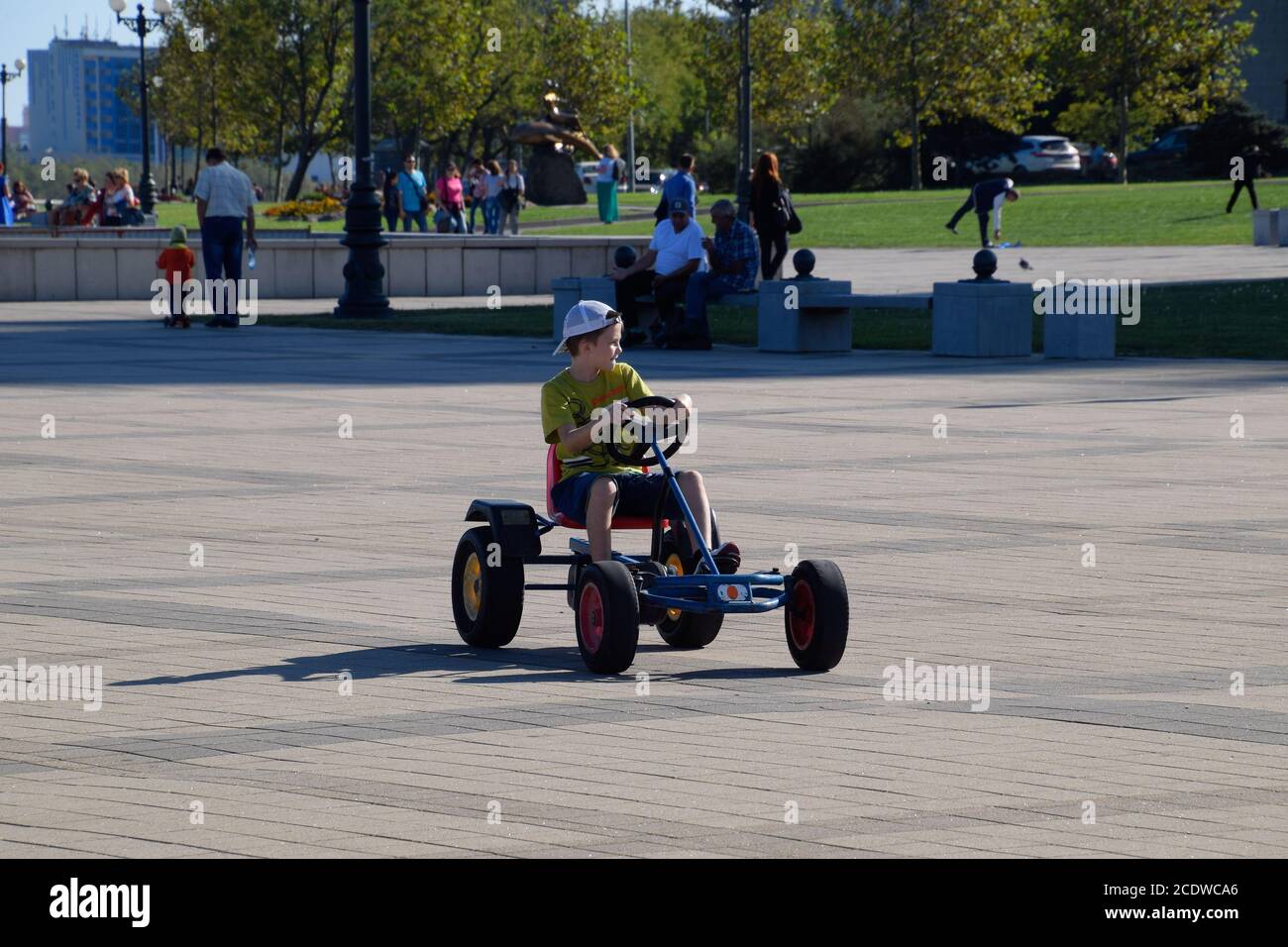 Children ride in the park on cars with pedals. Admiral Serebryakov Square. Childrens leisure. Stock Photo