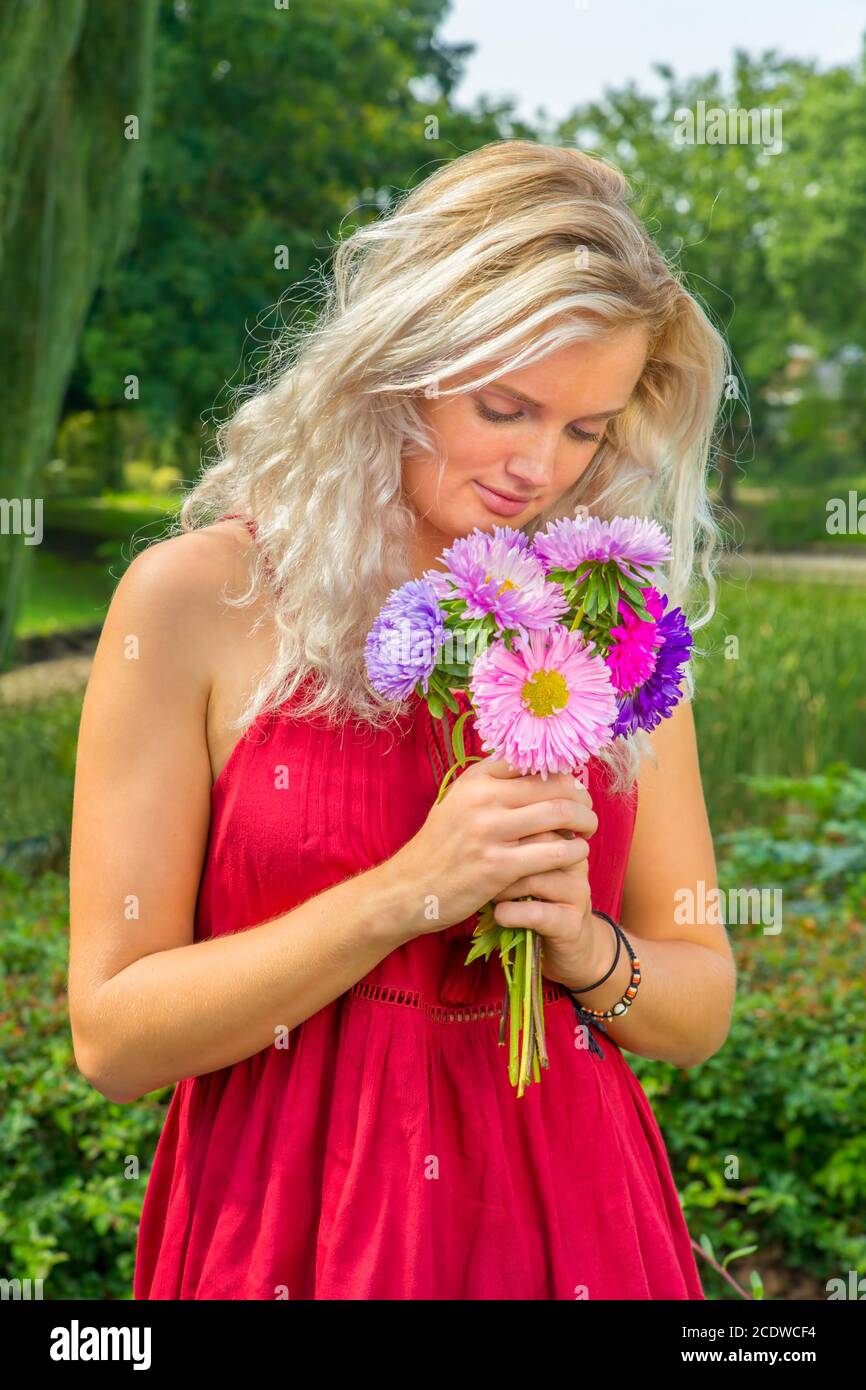 Young blond woman smelling summer flowers Stock Photo - Alamy