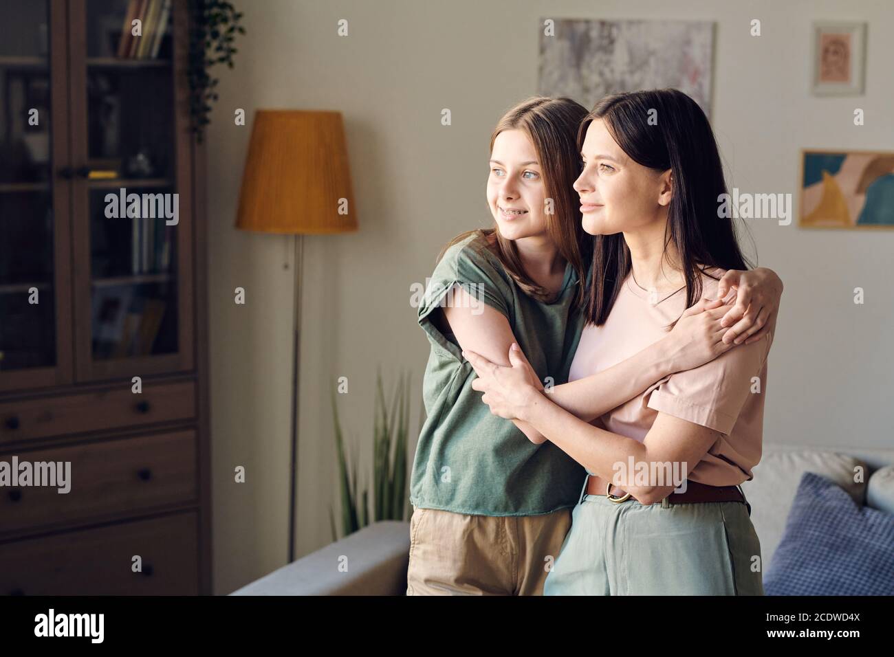 Two young pretty females with blond and dark long hair standing in embrace Stock Photo