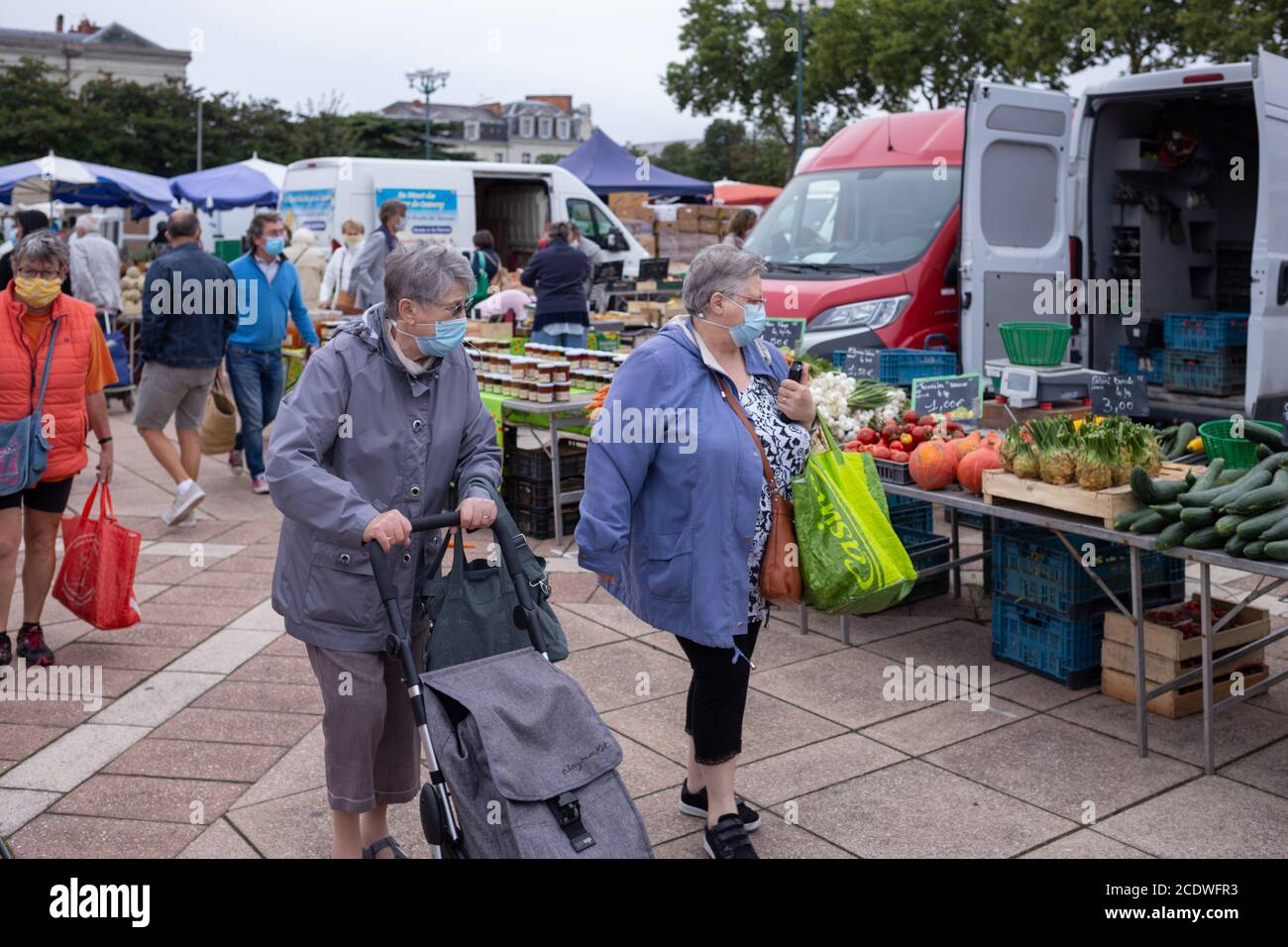 Angers, France - August 29 2020: people wearing face protective mask while shopping in the market place at France to prevent coronavirus, concept of wearing masks outdoor is mandatory in Europe, aged people Stock Photo