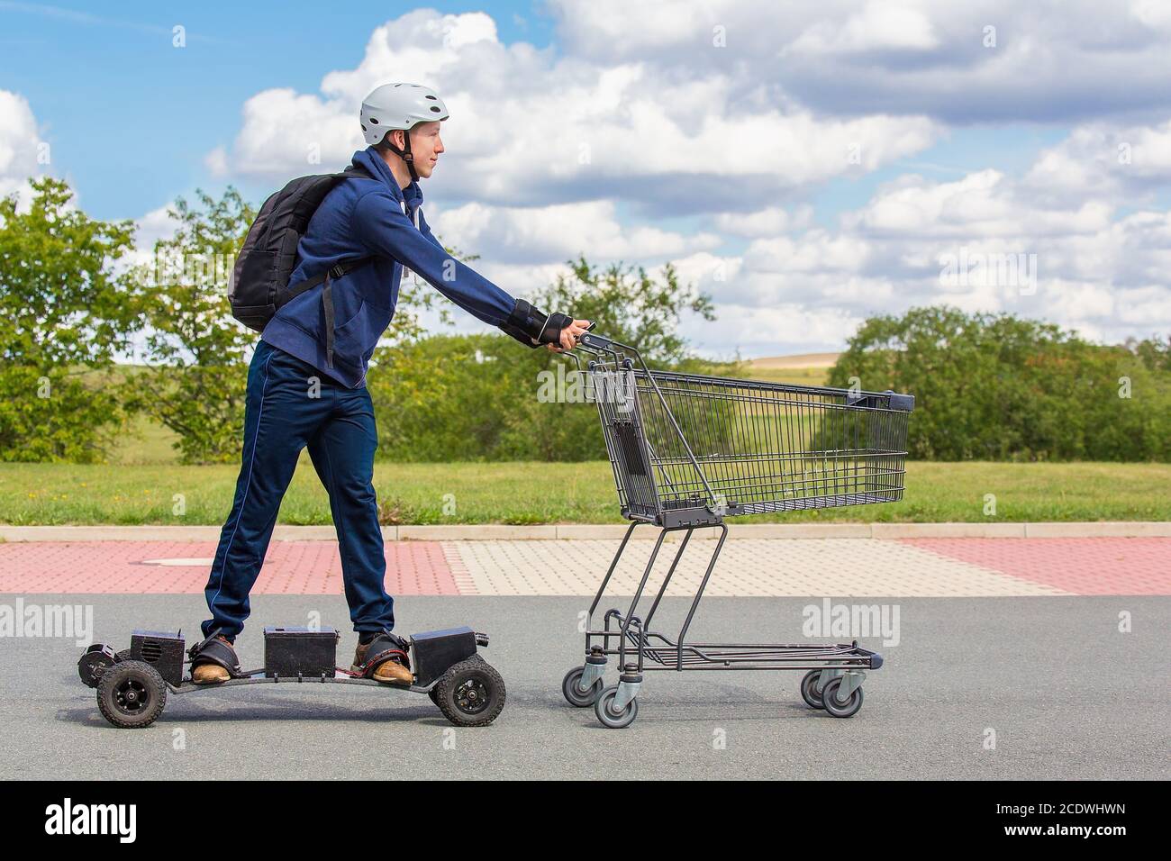 Boy on mountainboard pushing shopping cart outside Stock Photo