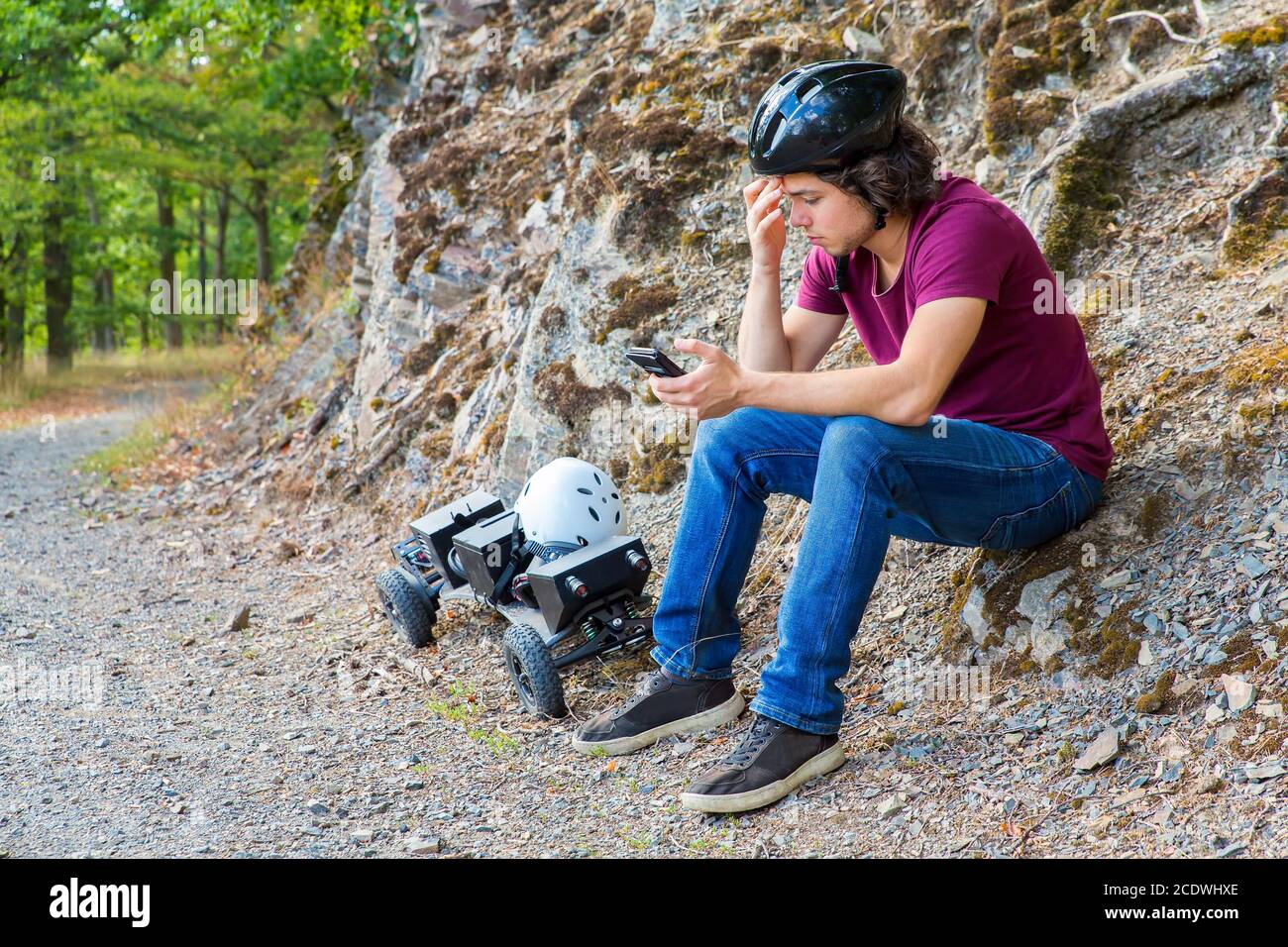 Young dutch man sits with mountainboard and cellphone Stock Photo