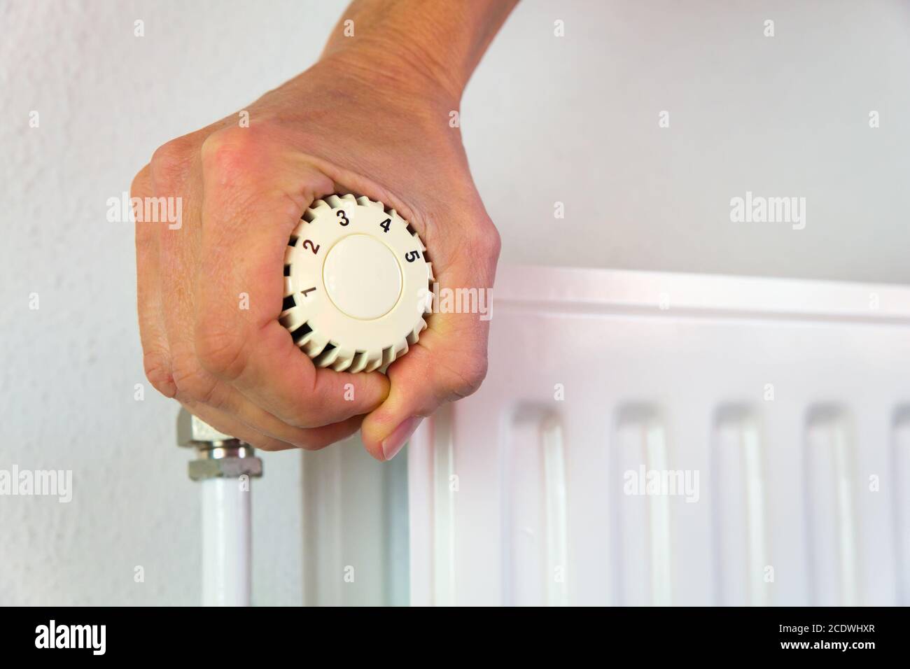 Hand turns heating valve open indoors Stock Photo