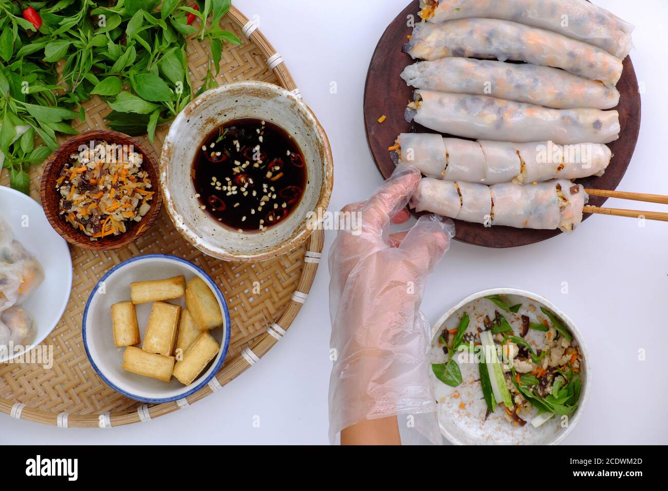 Vietnamese woman hand prepare breakfast, homemade vegan rice noodles roll from rice batter, mushroom, tofu, delicious vegetarian stuffed dish Stock Photo