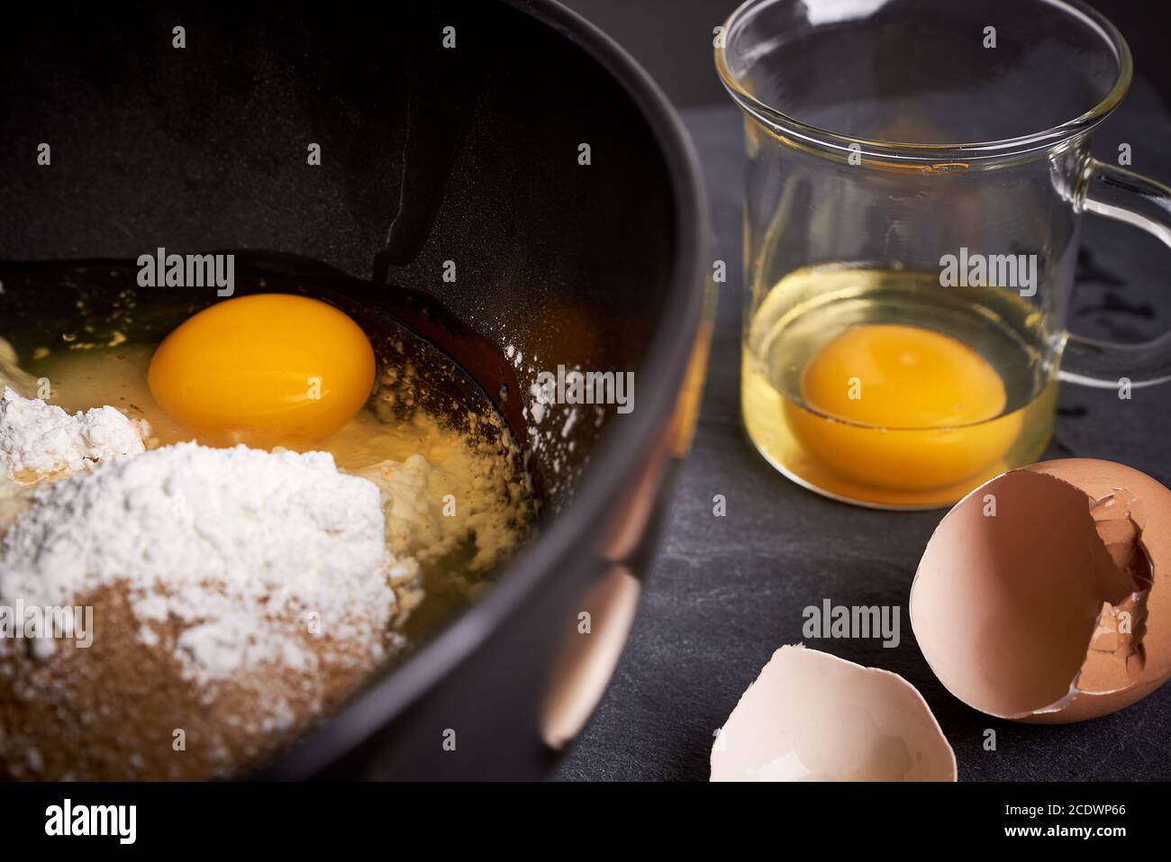 Mixing Bowl and Glass with Eggs, Flour and Sugar Stock Photo