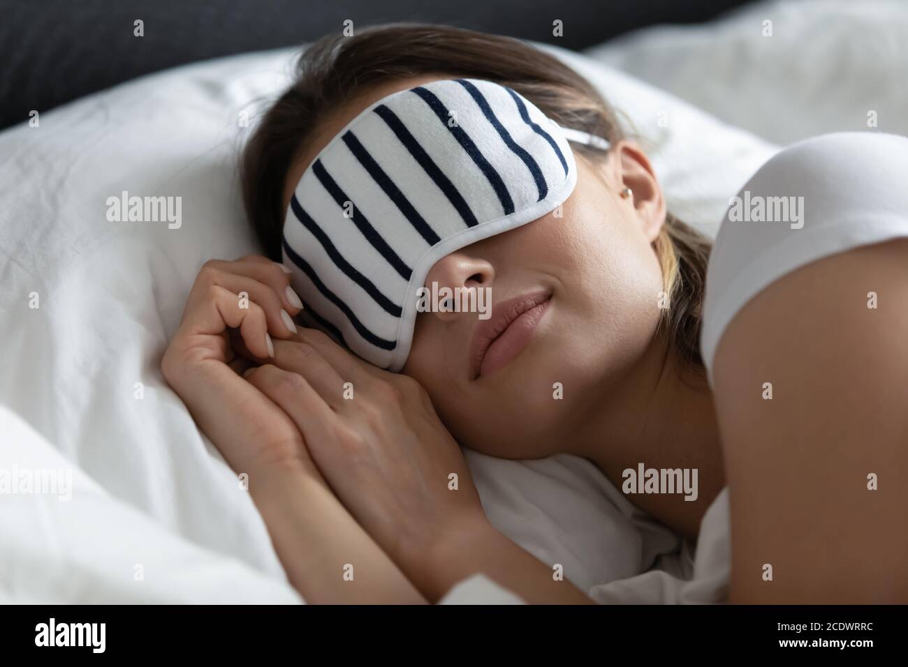 Close up peaceful young woman wearing stripped mask sleeping Stock