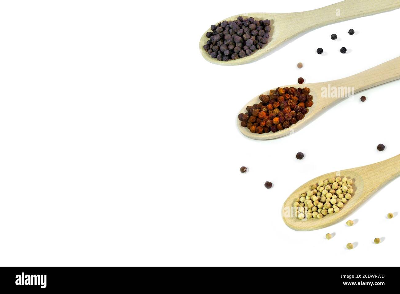 Black, red and white peppercorns close up, in wooden spoons on a white background isolated Stock Photo