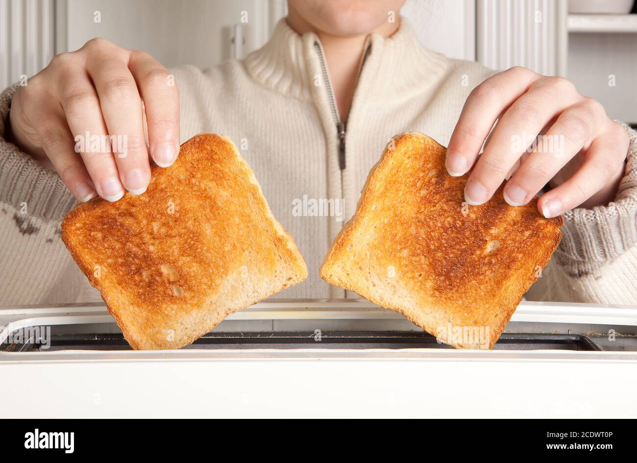 Hands of a woman taking fresh toast out of a toaster Stock Photo