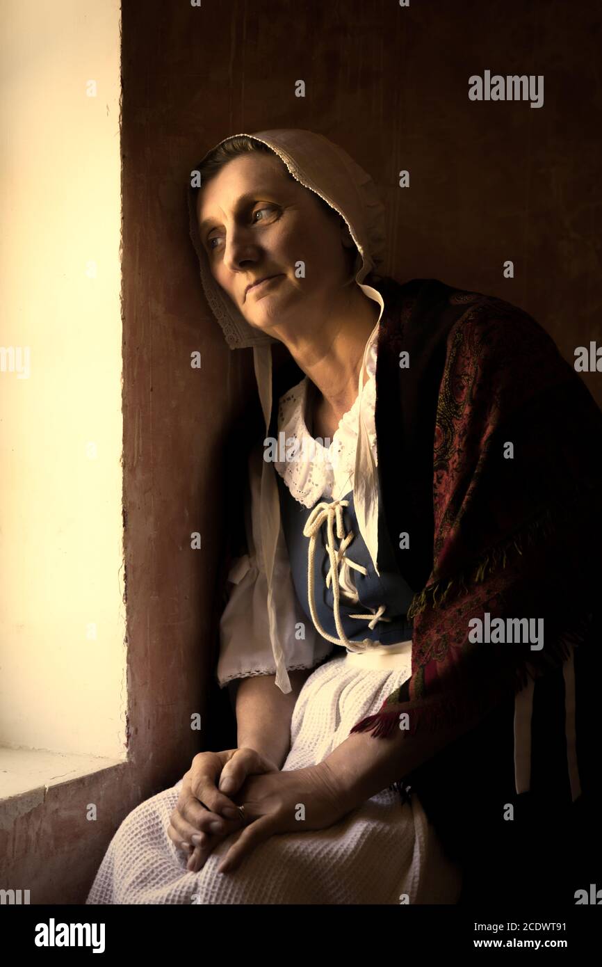 Vermeer or Rembrandt style portrait of a woman sitting at her window Stock Photo