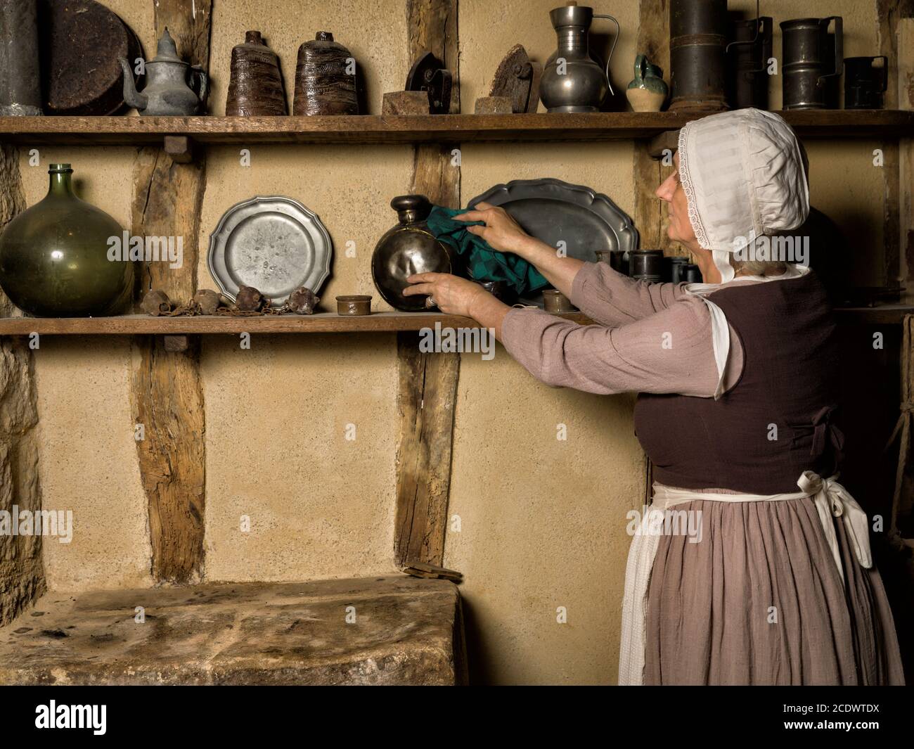 Woman dressed as a medieval peasant maid working in an authentic kitchen in a French castle Stock Photo