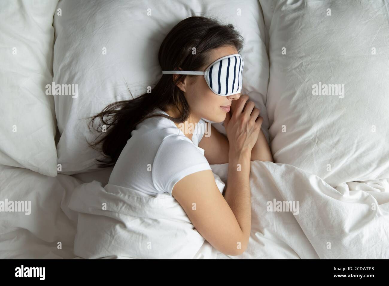 Top view peaceful young female wearing mask sleeping on side Stock Photo