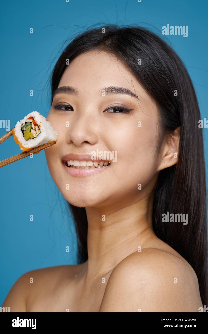 Woman holding chopsticks sushi rolls bared shoulders asian  Stock Photo