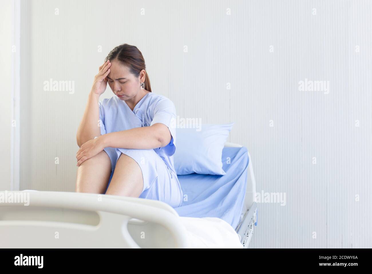 Asian female patients sitting in hospital beds showing discomfort Stock Photo
