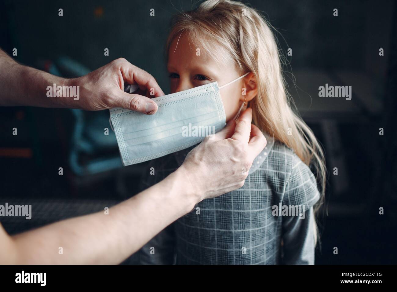 Parent helping daughter dressing uniform and put face mask preparation back to school Stock Photo