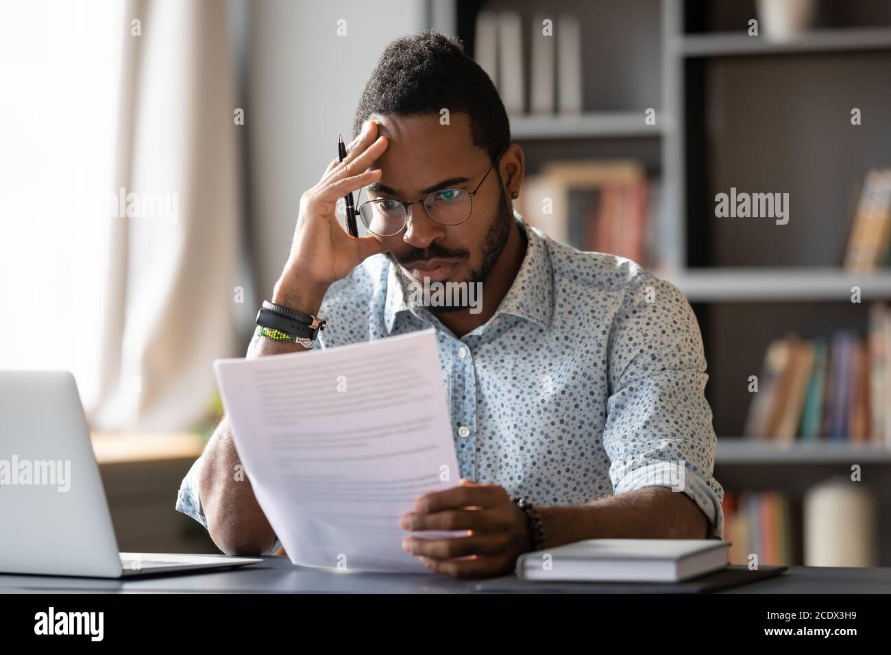African American man dissatisfied by bad news received in letter Stock Photo