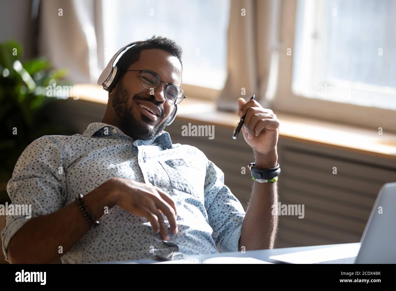 Satisfied relaxed African American man wearing headphones enjoying music Stock Photo