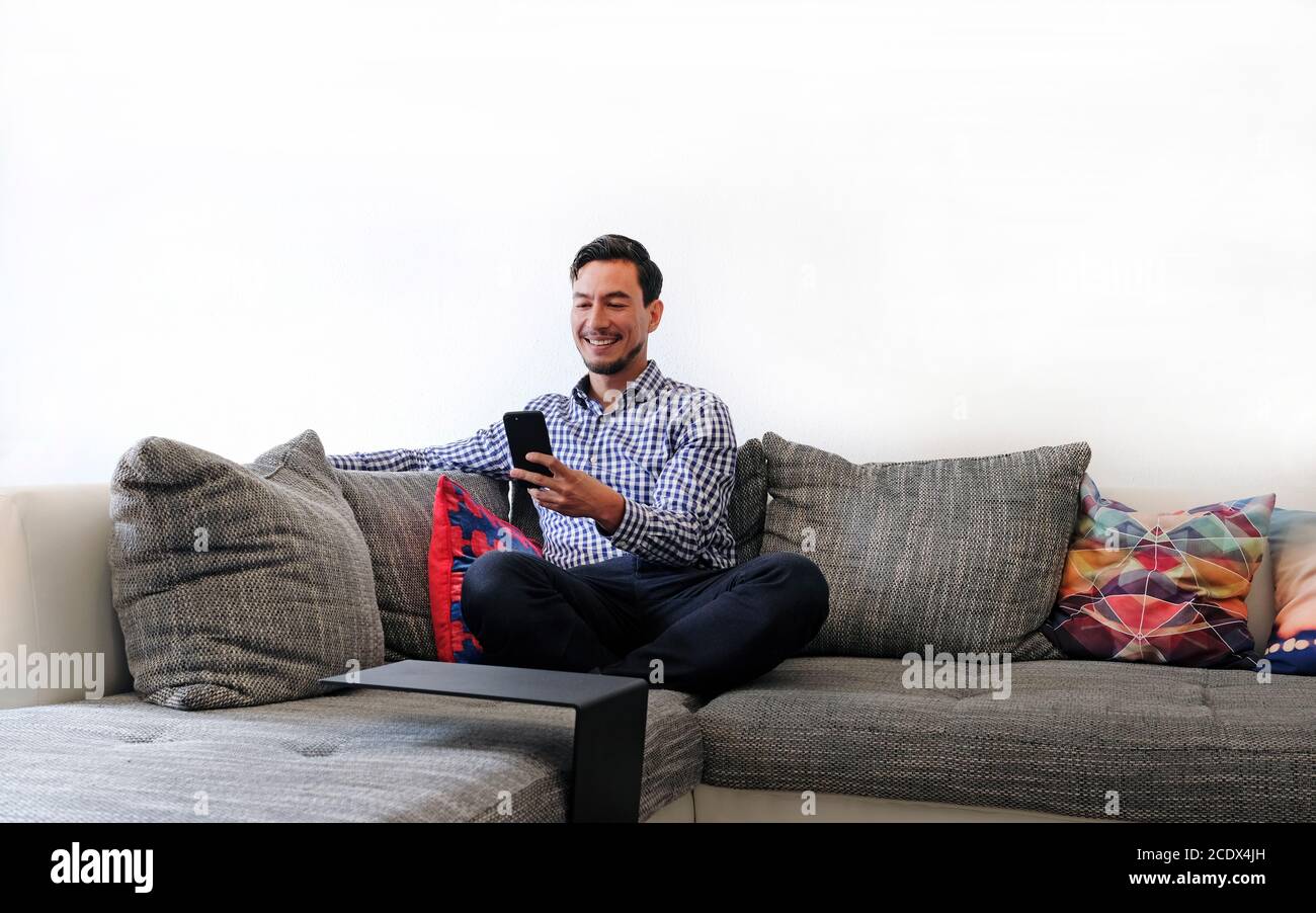 Smiling man typing on smartphone Stock Photo