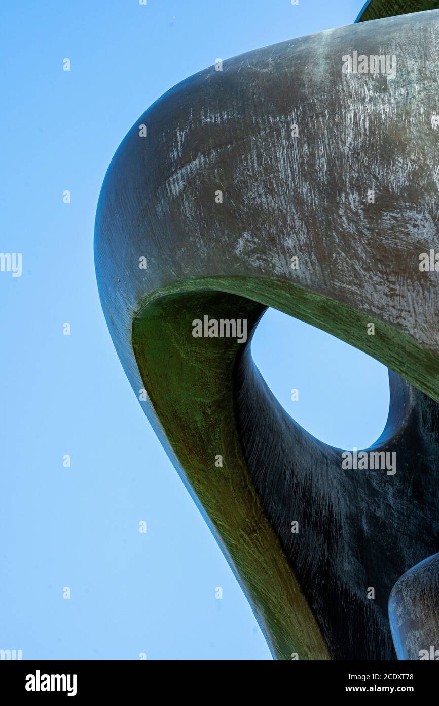 Large brass curved sculpture against blue sky textured background image abstract Stock Photo