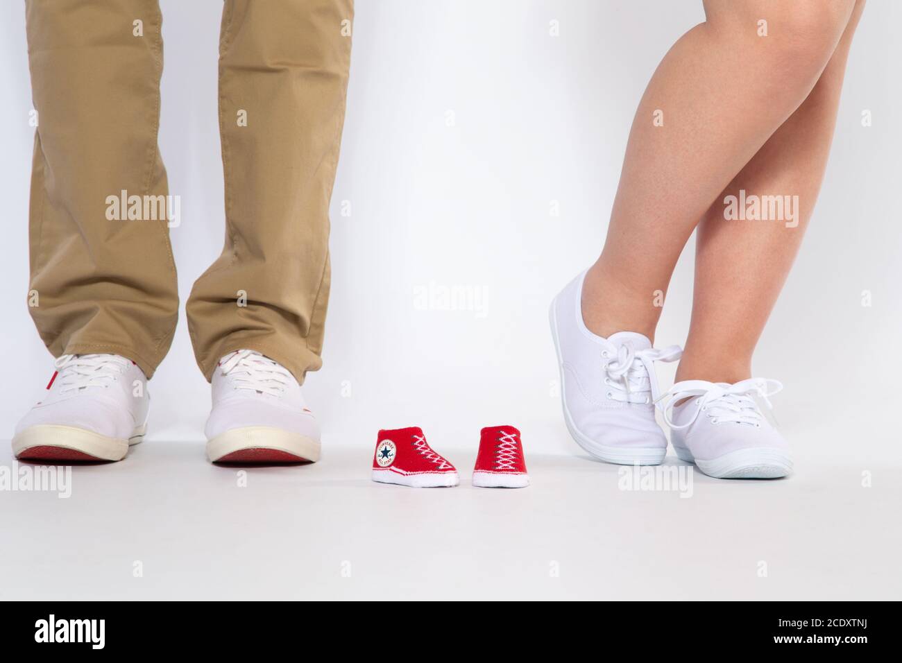Two pairs of feet from the parents and shoes from an unborn baby Stock Photo