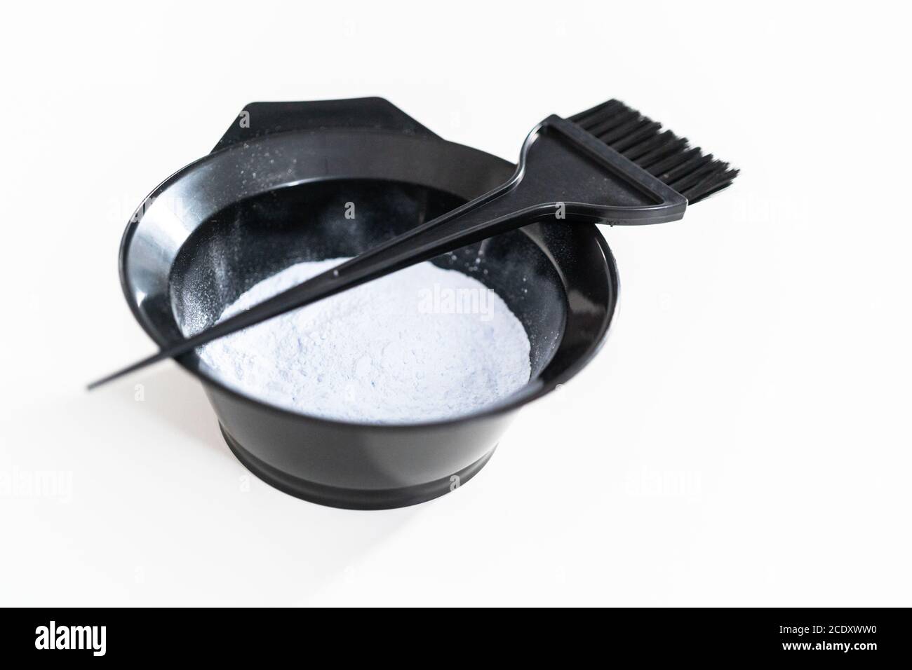 Hair color dye powder in a black plastic mixing bowl on a white