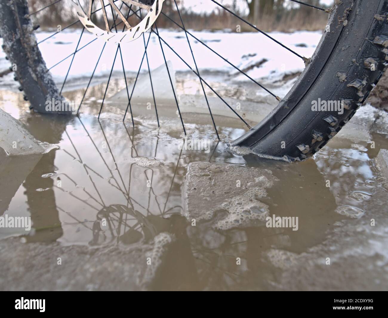 Bike drowned in muddy pool within winter trip. Broken pieces of ice around freeze terain tyre Stock Photo