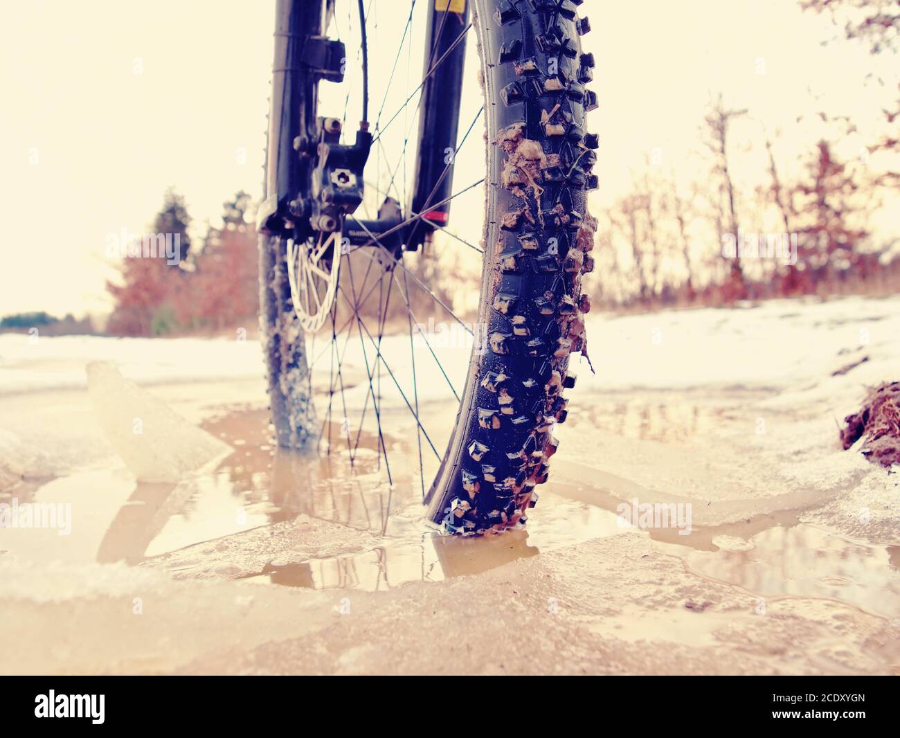 Extreme low ankle close view to mountain bicycle blocked in snowy icy trail.  Extreme wide view Stock Photo