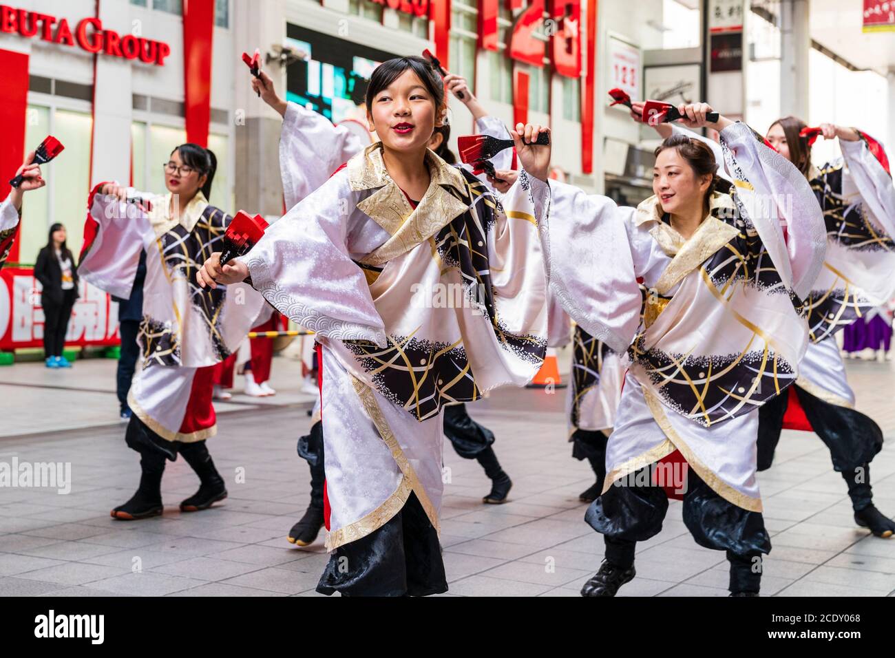 Japanese team of yosakoi dancers wearing long sleeved yukata dancing in shopping arcade during the Kyusyu Gassai festival at Kumamoto in Japan. Stock Photo