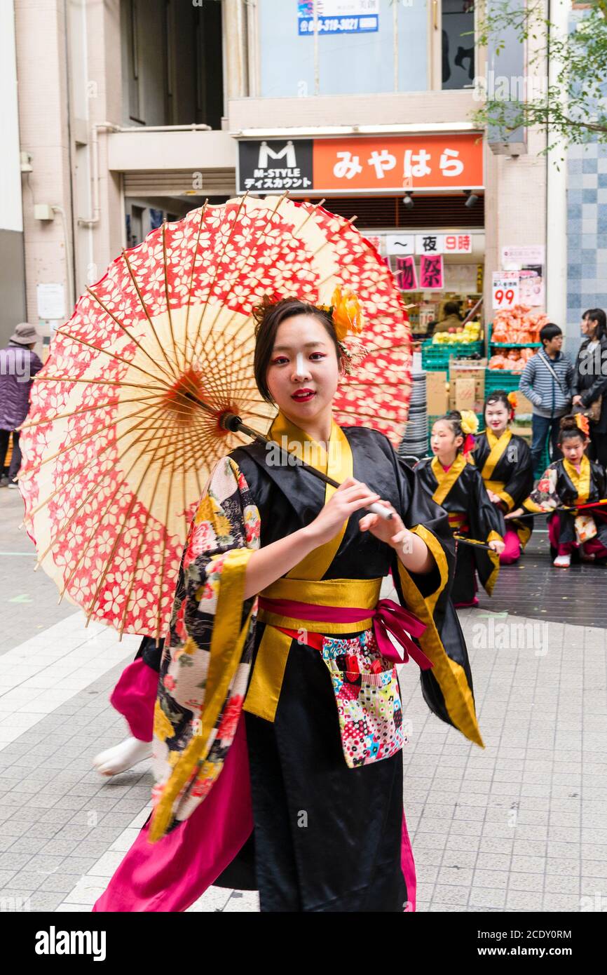 Close up of a Japanese women, part of a yosakoi dance team, dancing while holding a parasol and looking directly at viewer. Kyusyu Gassai festival. Stock Photo