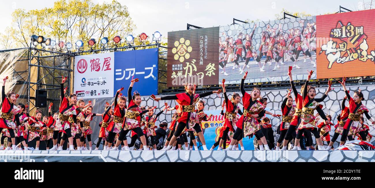 Team of Japanese child yosakoi dancers on stage dancing while using naruko, wooden clappers, during the Kumamoto Kyusyu Gassai dance festival in Japan Stock Photo