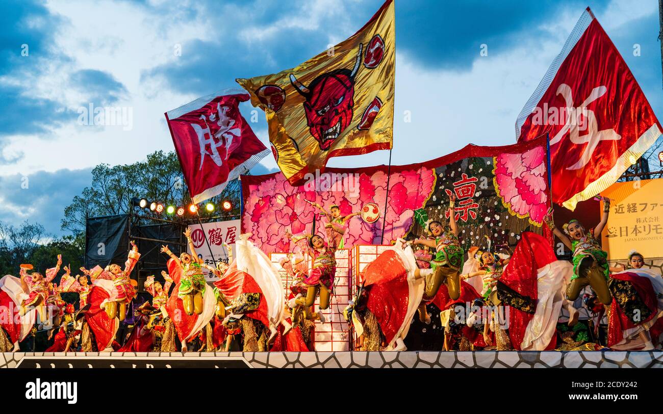 Team of Japanese child yosakoi dancers on stage dancing and jumping, holding naruko, wooden clappers. Kumamoto Kyusyu Gassai dance festival in Japan. Stock Photo