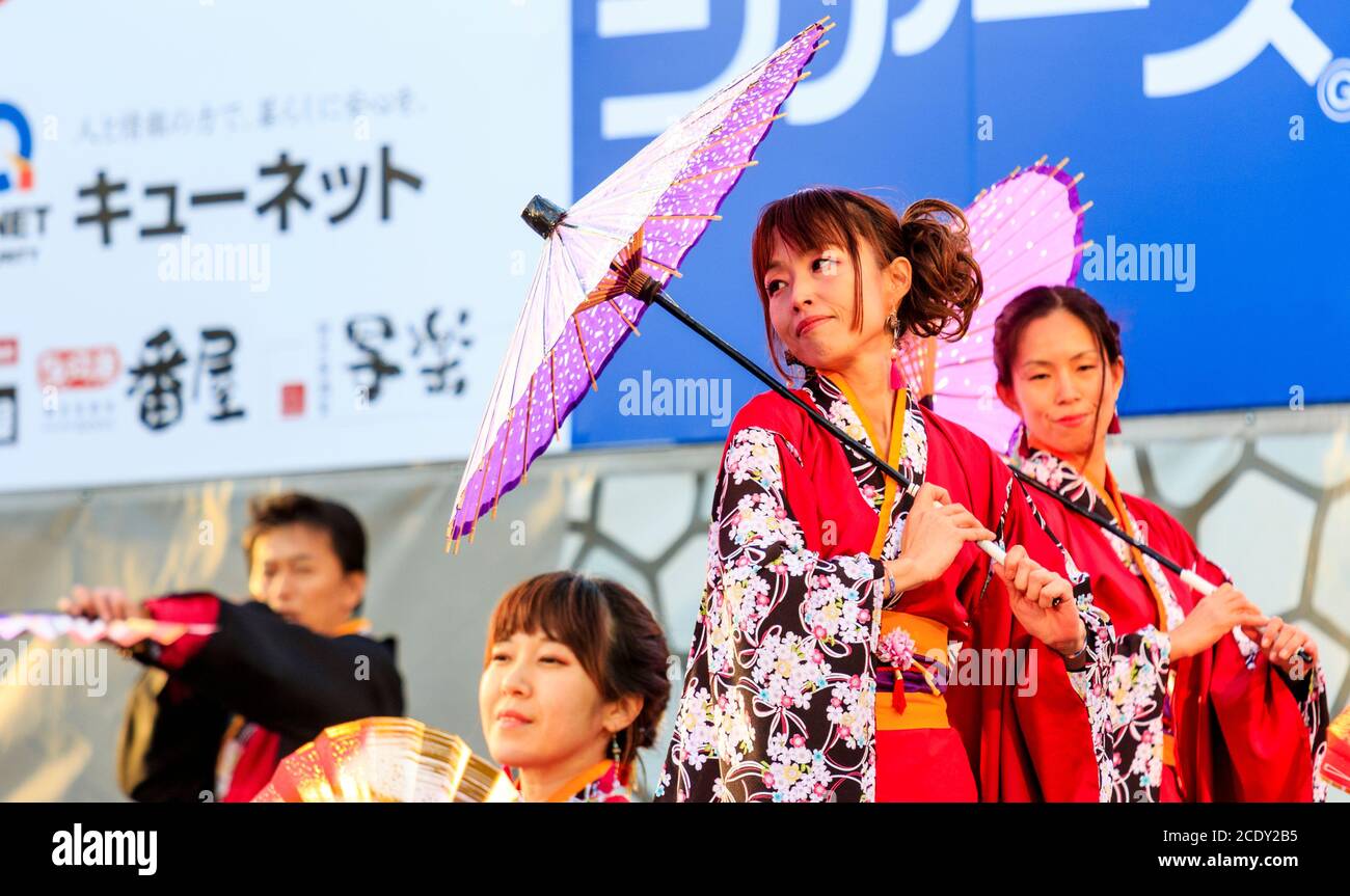 Japanese woman yosakoi dancer on stage, holding a parasol over her shoulder, dancing on stage at the Kyusyu Gassai dance festival, Kumamoto, Japan. Stock Photo